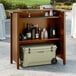 A Lancaster Table and Seating Vineyard Series portable bar with bottles and a cooler on top of it.