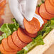 A person holding a slice of Before the Butcher plant-based pepperoni on a sandwich.