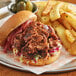 A sandwich with Before the Butcher plant-based pulled pork and fries on a plate.