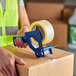 A person using a Lavex clear tape dispenser to seal a box.