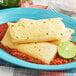 A plate of Tucson Foods Green Chile and Cheese Tamales with a lime slice on the side.