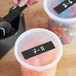 A plastic container of black Lavex masking tape on a counter with other containers of candy.