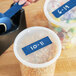 A hand using Lavex blue masking tape to label a plastic container of food.