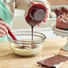 A hand pouring Lindt dark chocolate into a bowl of food.