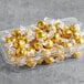 A plastic container full of gold foil wrapped Lindt Lindor white chocolate truffles.