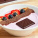 A bowl of yogurt with strawberries, blueberries, and Lindt dark chocolate.