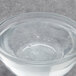 A clear glass bowl with clear liquid sitting in a clear glass bowl of water with bubbles.