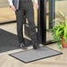 A man standing on a Lavex waffle entrance mat holding a book.