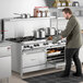A large stainless steel commercial range with ten burners and two convection ovens, shown in use in a professional kitchen.