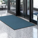 A blue Lavex parquet entrance mat on a floor.