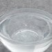 A clear glass bowl with clear liquid over a bowl of water with bubbles.