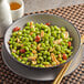 A bowl of shelled edamame on a table with chopsticks.