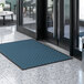 A blue Lavex parquet entrance mat on a marble floor.