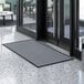 A gray Lavex Needle Rib entrance mat placed in front of a door.