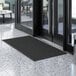 A black Lavex waffle entrance mat on a tile floor.