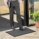 A man standing on a Lavex black parquet entrance mat holding a book.