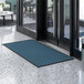 A blue and black Lavex parquet entrance mat on a white marble floor.