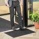 A man in a suit standing on a Lavex Needle Rib indoor entrance mat holding a folder.