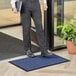 A man standing on a Lavex Needle Rib blue entrance mat in front of a door.