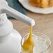 A glass with ice and Capora white chocolate flavoring sauce being poured into it.