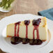 A slice of cheesecake with Capora blueberry sauce on top on a plate.