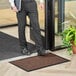 A man standing on a brown Lavex waffle entrance mat while holding a book.