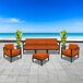 A BFM Seating Belmar outdoor sofa and chair set with orange Sunbrella cushions.