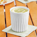 A World Centric reusable white PLA cup with a slice of lemon in it.