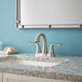 A Delta Lahara stainless steel deck-mount lavatory faucet with lever handles on a granite counter with a sink and mirror.
