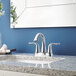 A Delta Lahara deck-mount lavatory faucet with lever handles and a metal pop-up drain on a bathroom sink with a flower.