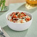 An American Metalcraft white melamine bowl filled with food with sauce.