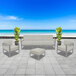 A white square ottoman with a gray cushion on a stone patio.