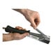 A close-up of a hand using a Surebonder Max Impact Heavy-Duty Hammer Tacker Staple Gun with a black handle.