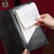 A hand holding a Choice tan and white guest check receipt in a black leather wallet.