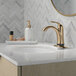 A bathroom sink with a Delta Champagne Bronze finish Delta Lahara deck-mount faucet and marble counter.
