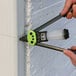 A hand using a Surebonder rivet tool to attach a rivet to a wall.