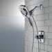 A Delta chrome shower head with a hand held shower head on a tile wall.