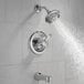 A close-up of a chrome Delta bath and shower handle with water flowing from a shower head.