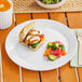 A World Centric reusable white PLA plate with a sandwich, salad, and drink on a table.