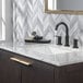 A white marble countertop with a Delta Nicoli matte black widespread deck-mount lavatory faucet and sink.