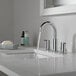 A bathroom sink with a Delta chrome widespread deck-mount faucet and lever handles running water.