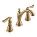A close-up of a Delta widespread deck-mount faucet with two lever handles in a matte champagne bronze finish.