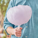 A man holding a large cotton candy made with Great Western purple grape floss sugar on a white stick.