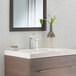 A white sink with a Delta Modern Series chrome lever faucet running over a vase of flowers.