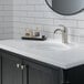 A bathroom sink with a Delta Lahara stainless steel deck-mount faucet and metal pop-up drain.