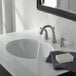 A Delta Lahara stainless steel widespread deck-mount lavatory faucet with lever handles running water into a white sink.