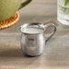 An American Metalcraft stainless steel bell creamer with milk in it.