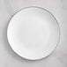 A Visions white plastic coupe plate with a silver rim.