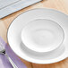 A Visions white plastic plate with a silver rim on a table.