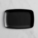 A black rectangular plastic Visions coupe platter on a marble surface.